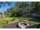 Manicured backyard with mature trees, green lawn and a cozy stone fire pit for outdoor gatherings at 5141 Mallet Dr, Port Richey, FL 34668