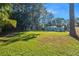 Expansive backyard with lush green grass, shade trees, and a charming cottage-style home at 5141 Mallet Dr, Port Richey, FL 34668