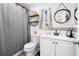 Bathroom with grey shower curtain, decorative mirror, toilet, and white vanity at 5141 Mallet Dr, Port Richey, FL 34668