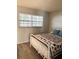 Cozy bedroom features wood-look floors and a comfortable white metal frame bed with a unique star-themed quilt at 821 Patricia Ave # 202, Dunedin, FL 34698