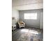 Bright bedroom featuring wood-look floors, a woven chair, neutral walls, and ample natural light through horizontal blinds at 821 Patricia Ave # 202, Dunedin, FL 34698