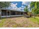 View of the backyard that includes the covered porch, tropical trees, and picnic table at 7814 34Th E Ct, Sarasota, FL 34243
