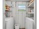 Functional laundry room with washer, dryer, shelving, and small window at 11923 Boynton Ln # B, New Port Richey, FL 34654