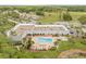 Aerial view of pool with orange lounge chairs in a courtyard surrounded by greenery, palm trees, and the community clubhouse at 11923 Boynton Ln # B, New Port Richey, FL 34654