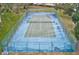 An aerial view of a fenced tennis court surrounded by green grass and shade trees at 150 Brent Cir, Oldsmar, FL 34677