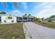 Charming single-story home with a yellow door and shutters, a long driveway, and lush landscaping at 456 Sandlewood Dr, Venice, FL 34293