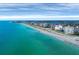 Expansive aerial view showcasing the coastline with its clear turquoise waters, sandy beach, and nearby buildings at 811 Laguna Dr, Venice, FL 34285