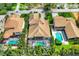 An aerial view of the tile roof home with screened-in pool area and lush landscaping at 811 Laguna Dr, Venice, FL 34285
