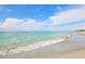 Calm turquoise water gently meets the sandy shore under a clear blue sky, inviting relaxation at 811 Laguna Dr, Venice, FL 34285