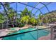 A screened pool with an attached hot tub and waterfall feature surrounded by lush landscaping at 811 Laguna Dr, Venice, FL 34285