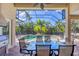 A screened-in patio is set up for outdoor dining with views of the pool, spa, and beautiful foliage at 811 Laguna Dr, Venice, FL 34285