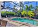 Screened pool area features lush landscaping, a safety fence, and an attached hot tub and waterfall feature at 811 Laguna Dr, Venice, FL 34285