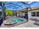 The screened in-ground pool features an attached hot tub and waterfall feature, and has a brick patio area at 811 Laguna Dr, Venice, FL 34285
