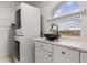 Convenient laundry area with stacked washer and dryer, sleek black bowl sink, and marble-look countertop at 15340 Alsask Cir, Port Charlotte, FL 33981