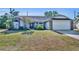 Charming home featuring a two-car garage, a lush front yard, and a welcoming entry door at 2601 Bridle Dr, Plant City, FL 33566