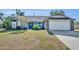 Charming home featuring a two-car garage, a lush front yard, and a welcoming blue entry door at 2601 Bridle Dr, Plant City, FL 33566