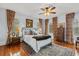 Bedroom boasts hardwood floors, detailed ceiling fan, patterned rug, and large windows with decorative drapes at 8407 Interbay Blvd, Tampa, FL 33616