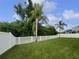 Spacious backyard with lush green grass, framed by a white picket fence and mature palm trees at 11356 Callaway Pond Dr, Riverview, FL 33579