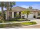 Inviting home exterior showcasing manicured landscaping, including palm trees, leading to the arched entryway and two-car garage at 11402 Peckham Pl, Tampa, FL 33625