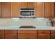 Close up of kitchen featuring stainless steel microwave, stone backsplash, and cooktop at 11402 Peckham Pl, Tampa, FL 33625