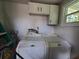 Laundry room featuring a white washer and dryer set with overhead storage cabinets at 13 Euclid Dr, Plant City, FL 33563