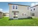 Backyard featuring lush green grass and a two-story home with sliding glass doors and an A/C unit at 1844 Brekey Way, Zephyrhills, FL 33541