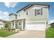 Exterior showcasing a two-story home with a two car garage, beautiful landscaping, and neutral-toned siding at 1844 Brekey Way, Zephyrhills, FL 33541