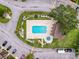 Aerial view of a community pool and jacuzzi surrounded by lush greenery, lounge chairs, and a restroom at 1200 Tarpon Woods Blvd # L4, Palm Harbor, FL 34685