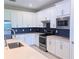 Well-equipped kitchen featuring modern appliances, white cabinets, light countertops and dark backsplash at 2729 Gabel Oak Dr, North Port, FL 34289