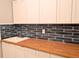 Laundry room showcasing custom cabinets, butcher block countertop, modern faucet, and unique blue backsplash at 2729 Gabel Oak Dr, North Port, FL 34289