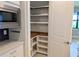 Well-organized pantry with built-in shelving offering ample storage space, adjacent to a modern microwave at 2729 Gabel Oak Dr, North Port, FL 34289
