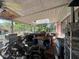 A covered porch area with stored items, including containers and a motorcycle, overlooking a green backyard at 1009 S Clark Ave, Tampa, FL 33629