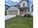 Two-story home featuring a landscaped yard, a gray garage door, and a charming peach-colored front door at 13707 Newbridge St, Spring Hill, FL 34609
