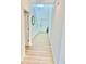 Bright hallway with wood-look flooring leads to a staircase and a white front door at 9937 Aqua Miles Path, Wesley Chapel, FL 33545