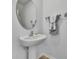 Elegant powder room with pedestal sink, oval mirror, and neutral decor showcasing simple sophistication at 9937 Aqua Miles Path, Wesley Chapel, FL 33545