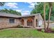 Exterior view of the brick home with manicured lawn and mature trees and landscaping at 15609 Timberline Dr, Tampa, FL 33624