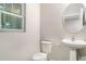 Powder room featuring modern fixtures, a pedestal sink, neutral paint, a round mirror, and a window at 12829 Scarlet Star Dr, Riverview, FL 33579