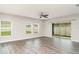 Living room featuring grey wood floors, neutral walls, ceiling fan, three windows, and sliding glass door at 12829 Scarlet Star Dr, Riverview, FL 33579