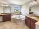 Elegant bathroom with a large soaking tub, dual vanities with granite countertops, and a window with a view at 19491 Paddock View Dr, Tampa, FL 33647