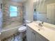 Bright bathroom featuring marble-look tile surround, bathtub and modern vanity at 9855 Morris Glen Way, Temple Terrace, FL 33637