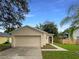 A single-story home featuring a two-car garage, neat landscaping, and an inviting front entrance at 9855 Morris Glen Way, Temple Terrace, FL 33637