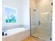 Bright bathroom featuring a tub under a window and a modern glass enclosed shower at 14073 Naylor Ave, Port Charlotte, FL 33981