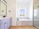 Modern bathroom with vanity, soaking tub under a window, and glass-enclosed shower at 14073 Naylor Ave, Port Charlotte, FL 33981