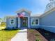 Close-up of the home's facade featuring a gray frame, an American flag, and well-maintained landscaping at 14073 Naylor Ave, Port Charlotte, FL 33981