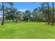 Expansive backyard featuring lush lawn, mature trees, and play equipment at 15364 Mount Sparrow Rd, Weeki Wachee, FL 34614
