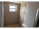 Bathroom with tiled walk-in shower, window, and standard toilet at 9825 Sandstone Ln, Port Richey, FL 34668