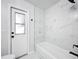 Bright bathroom featuring white marbled tile and a white bathtub with modern black fixtures at 142 Broadmoor Ln, Rotonda West, FL 33947