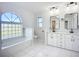 Bright bathroom featuring double vanities, an arch window, and a tub showcasing contemporary design at 142 Broadmoor Ln, Rotonda West, FL 33947