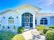 Close-up showcasing the home's arched, screened entry, complemented by stylish windows and fresh landscaping at 142 Broadmoor Ln, Rotonda West, FL 33947
