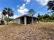 Back of house showcasing modern design and a spacious backyard with palm trees and blue sky at 1495 Craleigh St, North Port, FL 34288